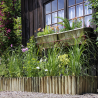 Bordure en bois en rouleau 175cm mise en situation devant une maison, délimitant un massif de plantes