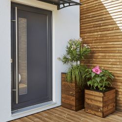 Bac à fleurs haut carré COLLECTORS en situation, devant une entrée de maison à côté d'un bac à fleurs de la même collection